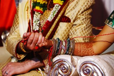 Midsection of couple holding hands in wedding ceremony