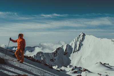 Woman skiing on snowcapped mountains against sky