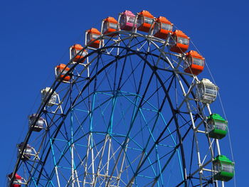 Low angle view of ferris wheel against clear blue sky