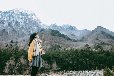 Rear view of person standing on mountain during winter