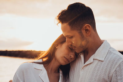 Side view of young man looking away against sky during sunset