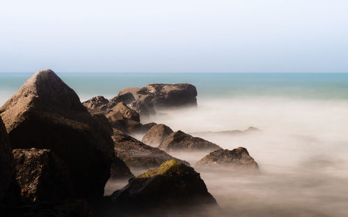 Scenic view of rocks in sea against sky