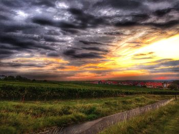 Scenic view of dramatic landscape against cloudy sky during sunset