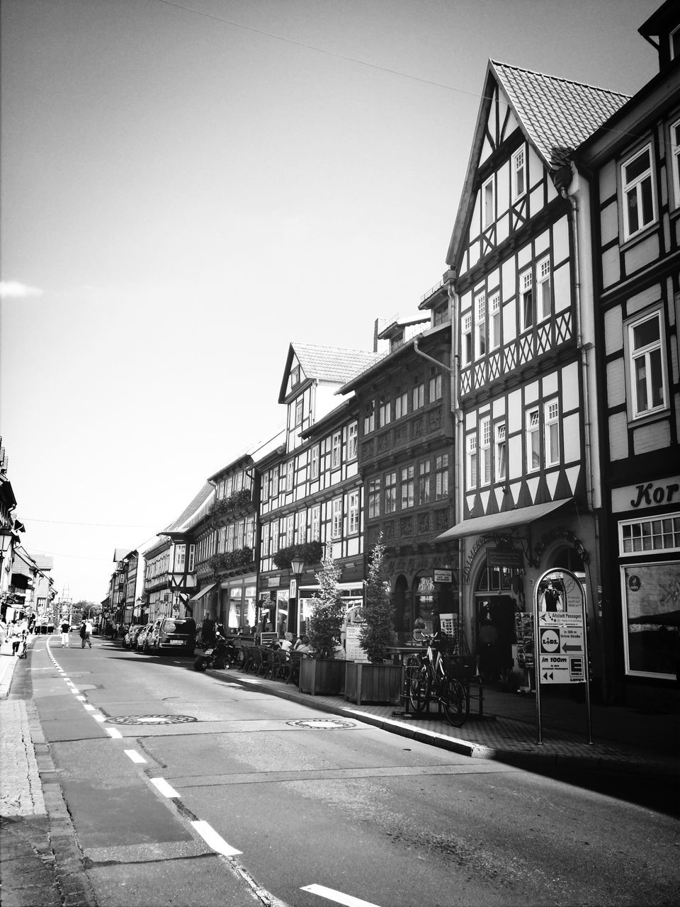 architecture, built structure, building exterior, transportation, street, road, car, city, clear sky, land vehicle, mode of transport, road marking, the way forward, building, city street, sky, incidental people, diminishing perspective, city life, outdoors