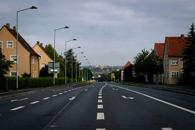 Road by buildings in city against sky