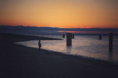 Silhouette pier on sea at sunset