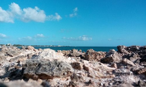 Rocks on beach against blue sky