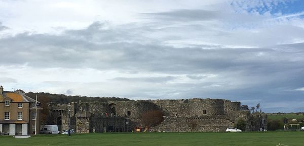 Old building in field against cloudy sky