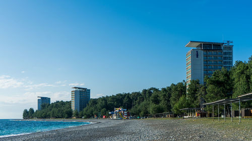 Buildings by street against blue sky