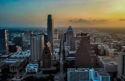 Aerial view of buildings in city against sky during sunset