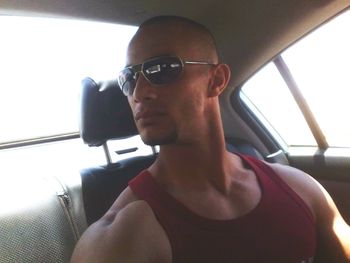 Young man wearing sunglasses in car against sky