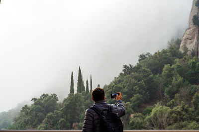 Rear view of man photographing against sky