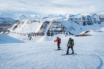 Man and woman skiing in iceland with mountains in background