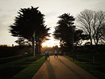 People walking on road at sunset