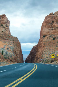 Road leading towards mountains against sky