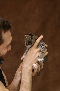 Man plays with a kitten. hugs him and kisses him