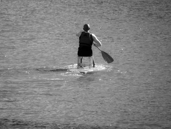 Rear view of man paddleboarding in sea