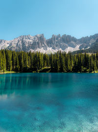 Scenic view of lake by mountains against clear blue sky