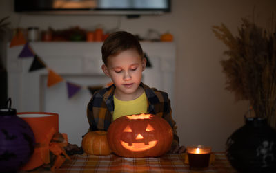 Portrait of boy playing with jack o lantern at home
