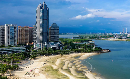 Modern buildings by sea against sky in city