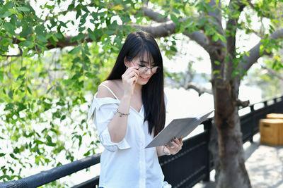 Young woman standing against plants