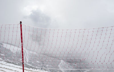 Red mesh in the mountains for fencing. restriction in the snowy mountains. low cloudiness. fog. 