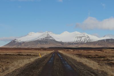 Road amidst snowcapped mountains against sky