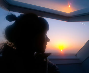 Close-up of boy against sky during sunset