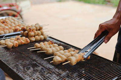 Midsection of person preparing food on barbecue grill