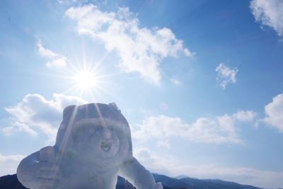 Low angle view of woman holding sun against sky