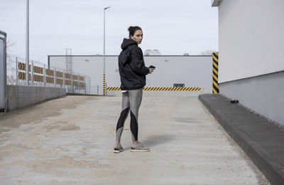 Portrait of woman listening music while standing on terrace