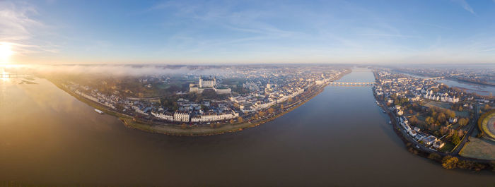 Aerial drone view of saumur medieval castle, saint peter church and loire river at sunrise, france