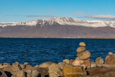 Scenic view of sea by mountains against sky