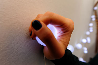 Close-up of hand holding camera against wall