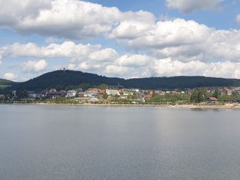 Scenic view of sea by townscape against sky