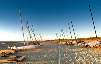 Boats moored on beach against clear blue sky