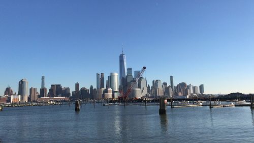 View of city buildings by sea against sky