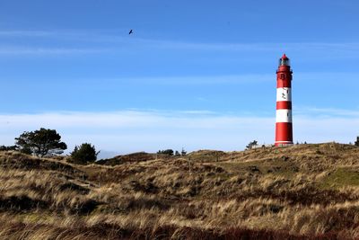 Lighthouse on field against sky