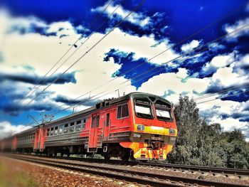Train on railroad track against cloudy sky
