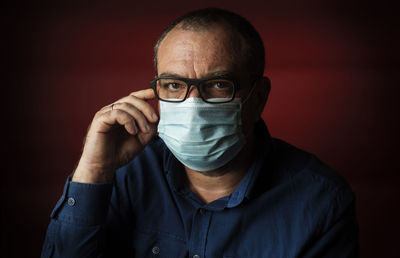 Close-up portrait of man wearing eyeglasses against black background