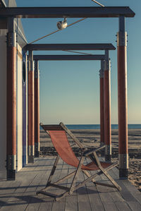 Deck chair on beach against clear sky