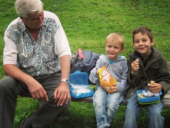 Full length of father and daughter eating while sitting outdoors