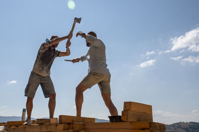 Low angle view of men jumping against sky