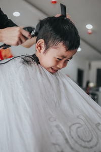 Cropped hand of person cutting boy hair at salon