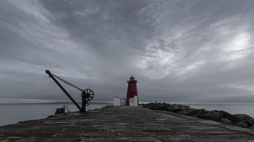 Lighthouse by sea against sky