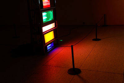 Illuminated electric lamp on floor against wall at home