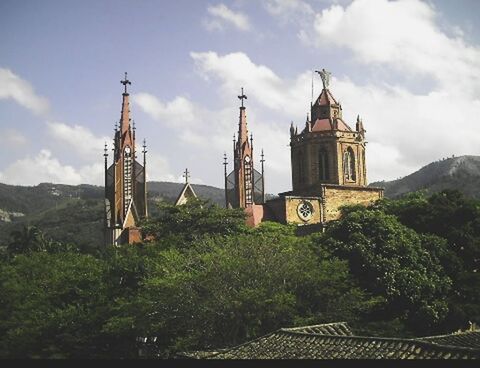 architecture, built structure, building exterior, religion, place of worship, church, spirituality, sky, tree, low angle view, cloud - sky, tower, steeple, cathedral, cross, cloud, clock tower, day