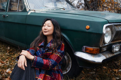 Portrait of smiling young asian woman near retro car