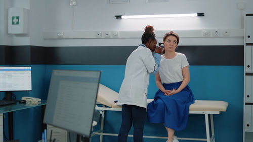 Doctor examining patients ear at hospital
