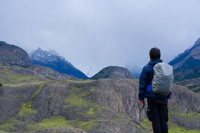 Rear view of man standing on mountain against sky